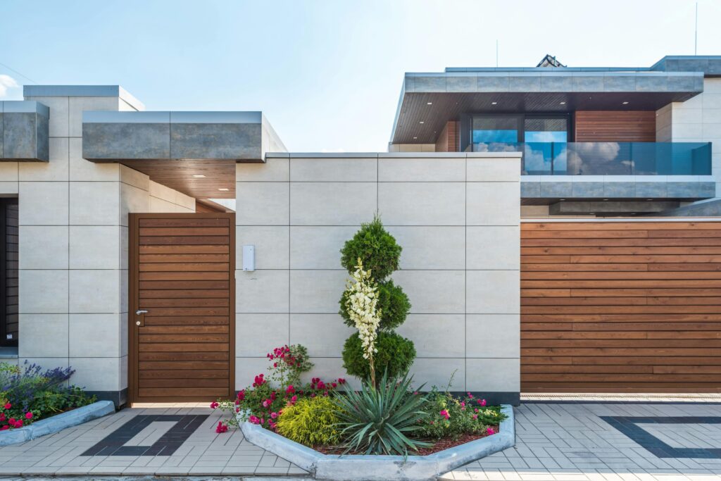 Contemporary house exterior featuring a stylish wooden facade, entrance gate, and vibrant garden.